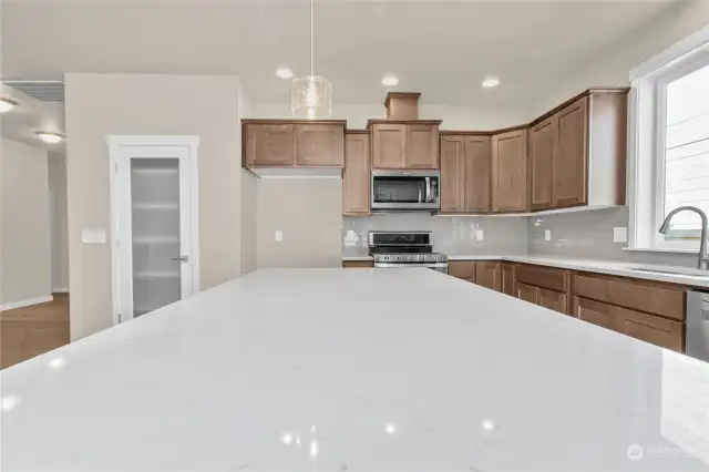 The oversize island provides additional space for meal preparation or quick and convenient dining options. Photo from same plan on different lot, finishes and features will vary.