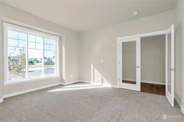 Drenched in natural light, the front bedroom features modern and glass panel French doors. Photo from same plan on different lot, finishes and features will vary.