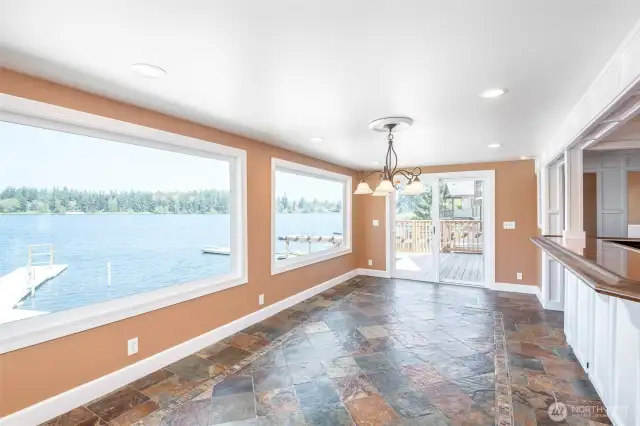 Large dining area with panoramic views of the lake and door to deck
