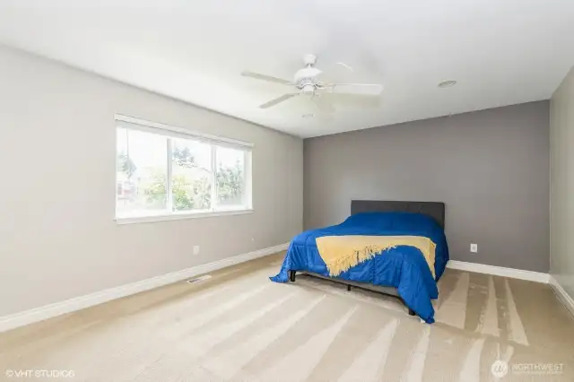 "Spacious primary suite with ceiling fan and large windows for natural light."