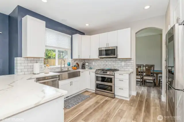 "Modern kitchen with quartz countertops, double oven with gas range, subway tile backsplash, and white shaker cabinets."