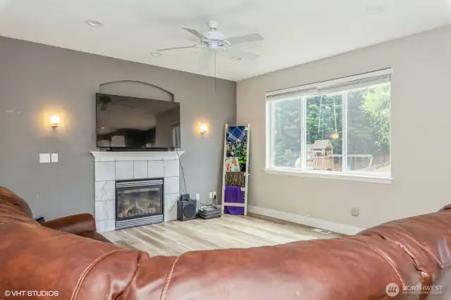 luxury vinyl flooring, a cozy gas fireplace, large windows with natural light, and seamless flow to the kitchen—perfect for relaxing or entertaining.