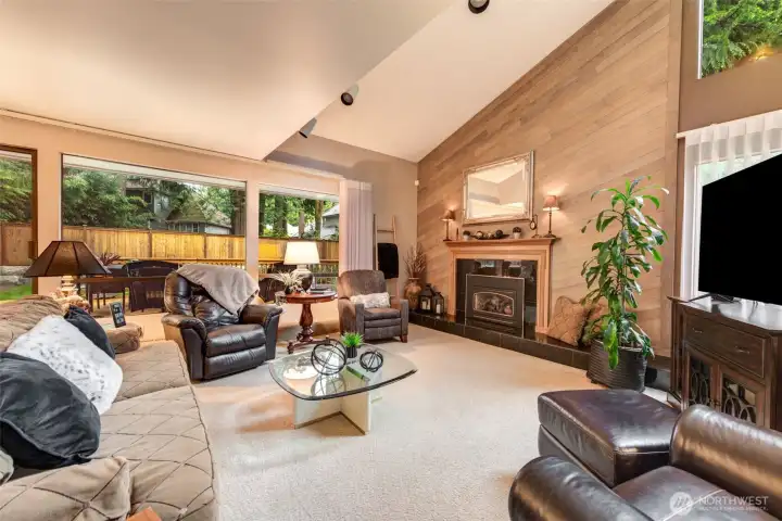 Light and bright living room with vaulted ceiling, cedar fireplace wall, and wall-to-wall windows