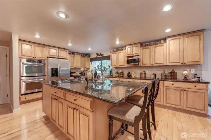 Expansive kitchen with double oven, trash compactor, dishwasher, refrigerator, ample cupboard and counter space