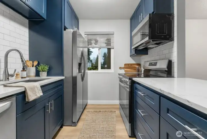 Updated modern kitchen featuring quartz countertops, custom cabinets, stainless steel appliances, and tiled backsplash.