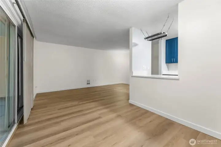 Fresh white paint and brand-new LVP flooring create a clean, cohesive flow throughout the open living and dining spaces, leading seamlessly to the spacious private patio.