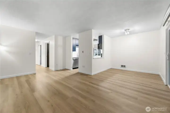 Fresh white paint and brand-new LVP flooring create a clean, cohesive flow throughout the open living and dining spaces, leading seamlessly to the spacious private patio.