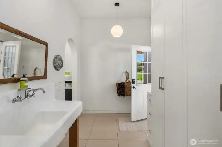 Step in from your own private park-like setting into the utility room featuring a designer farmhouse sink and a conveniently located powder bath just off the kitchen.