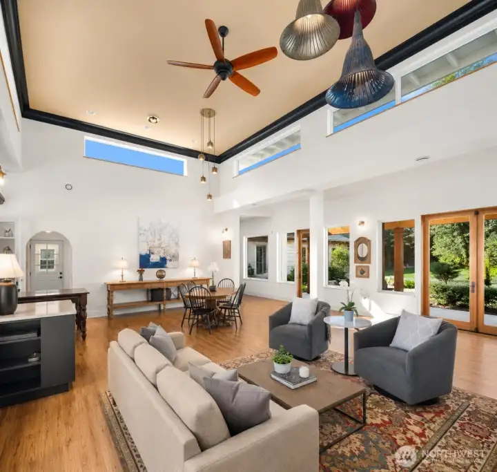 Soaring ceilings frame breathtaking sunset sky views, while expansive doors open seamlessly to both the inner courtyard and covered outdoor living spaces.