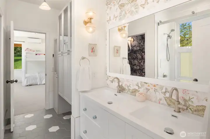 The Jack-and-Jill bath showcases floating cabinetry, abundant storage, designer wall tile, and oversized windows that invite refreshing breezes while you relax in the soaking tub.