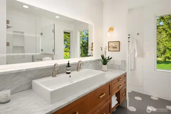 The spa-inspired bath features marble countertops, a full-height marble backsplash, radiant heated floors, and serene water views to enjoy while soaking in the tub.