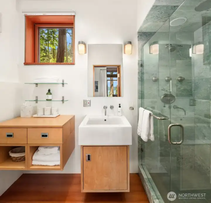The bath features radiant heated floors, spacious designer showers with full tile surrounds, and sleek modern finishes throughout.