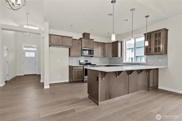Kitchen features Sable-stained Maple Shaker-style cabinets with quartz countertops and full tile backsplash and extended eating bar.