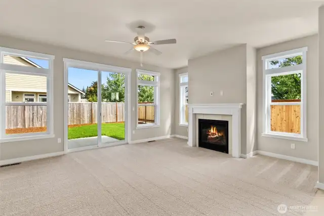 Living room with plenty of natural light featuring cozy gas fireplace with tile surround and ceiling fan.