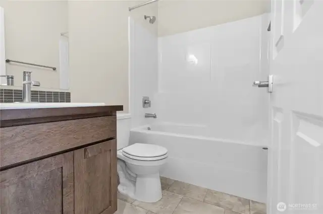 Full bathroom with undermount sink in Shadow-stained Maple cabinetry, quartz countertop with backsplash and tub/shower.