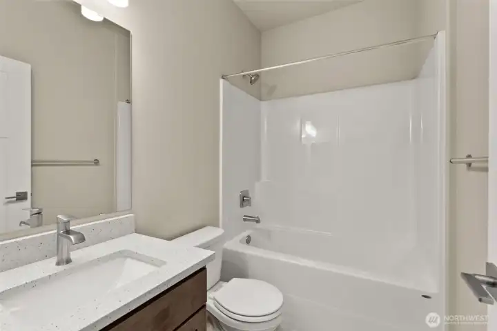 Full bathroom with undermount sink in Shadow-stained Maple cabinetry, quartz countertop with backsplash and tub/shower.