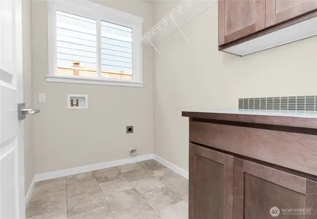 Separate laundry room with cabinets and a high hanging shelf for extended storage.