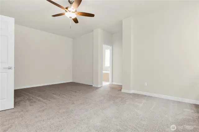 Inviting and spacious primary bedroom with ceiling fan for added comfort.
