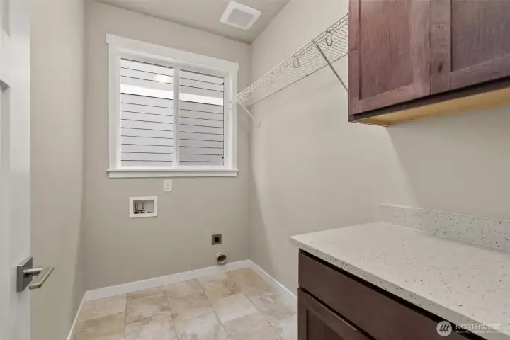 Separate laundry room with cabinets and a high hanging shelf for extended storage.