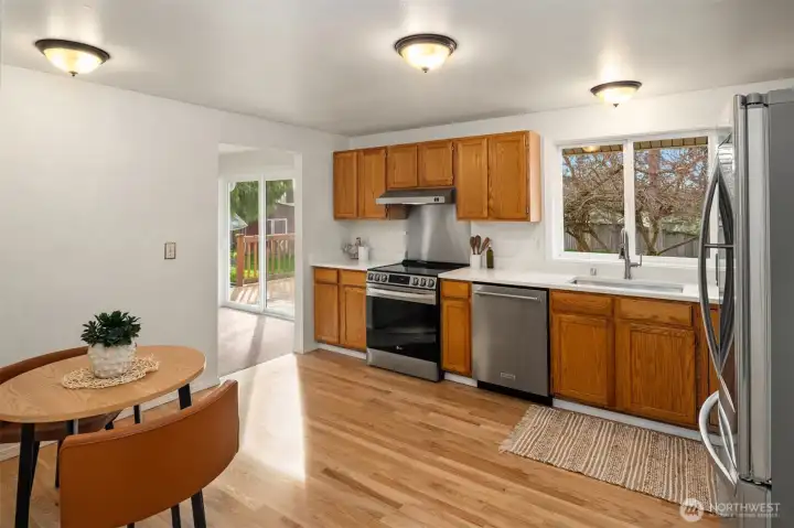 Kitchen features refinished oak cabinets, brand new quartz countertops, stainless steel appliances, refinished hardwood floors, and a small eating nook.