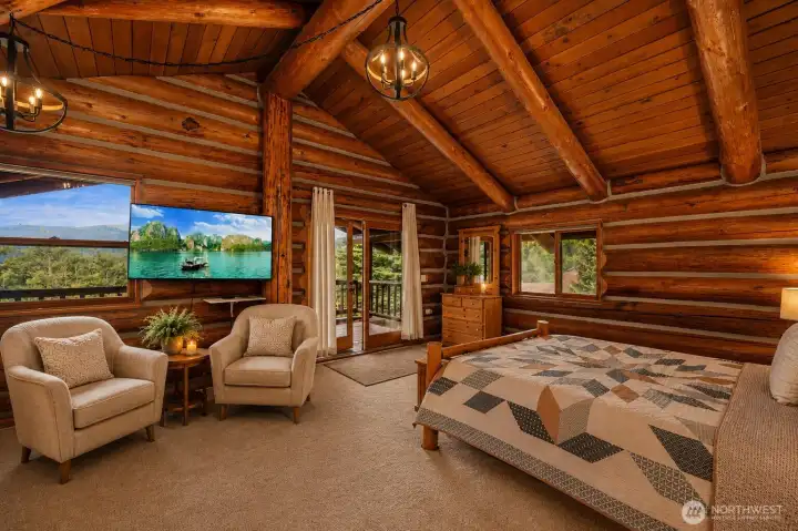 Upstairs, the private primary suite features a cozy sitting area, French doors, and beautiful beamed ceilings that enhance the warm lodge-style ambiance.