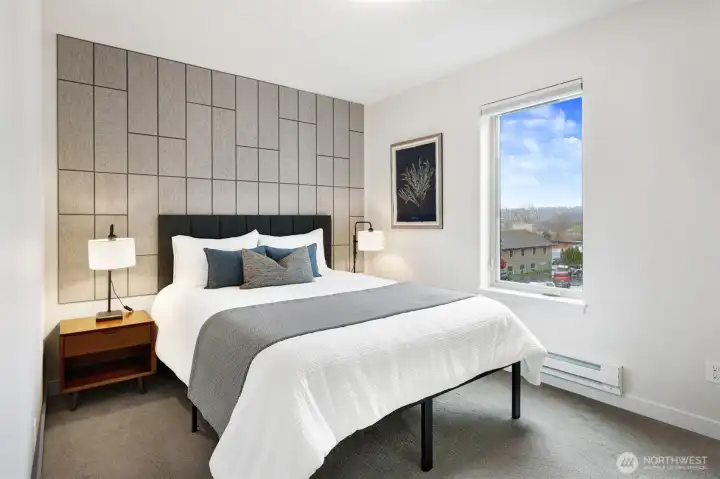 The primary bedroom (with a peek of Lake WA) is bright and spacious, with custom wool soundproofing on the wall for a peaceful night's sleep, every night.