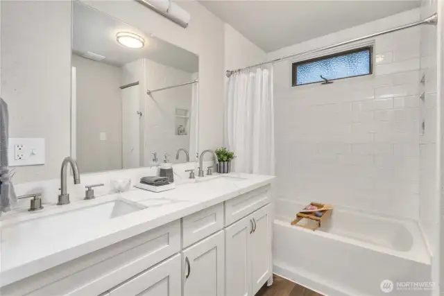 Main floor bathroom offers a soaking tub/shower w/ tiled walls and double sink vanity.