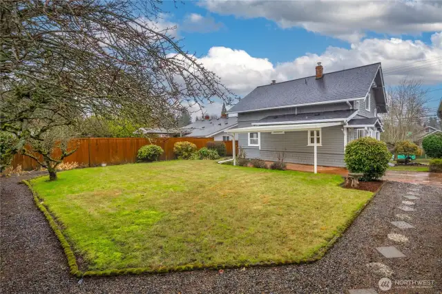 Standing at the one-car detached garage, showing the backyard, covered patio, and NEW roof.