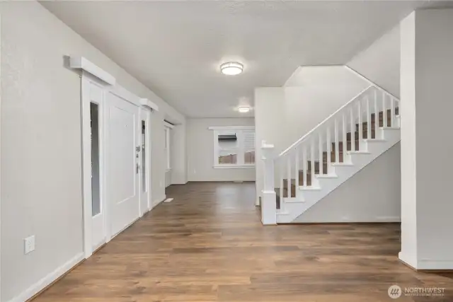 Original front door has the classic side panel windows to let the light in. This view is standing in the living room, looking straight ahead toward the dining room. The hall on the right leads to the main level bedroom.