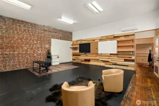 Front room designed with wood designed entertainment wall, concrete floors, hardwood floors, brick walls.