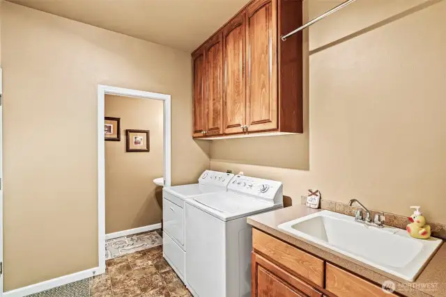 Large laundry with hardwood cabinetry, utility sink plus well-placed half bath for ease of use while working outside in the garage, yard or shop.