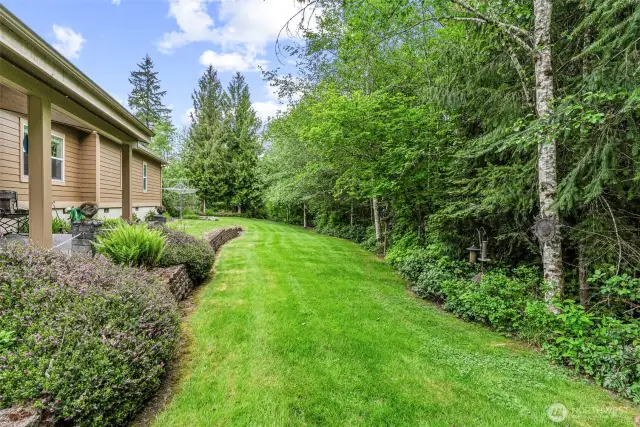 The lawn continues around the back side of home bordered by natural landscaping, terraced walls and pops of seasonal color. Listen to the birds and watch them happily visit well-placed feeders.