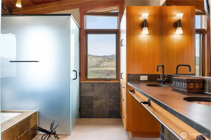 The primary bath has just the right mix of stone and glass, concrete and wood for a clean aesthetic. Double sinks, frosted glass toilet and shower compartments, and a wonderful soaking tub.