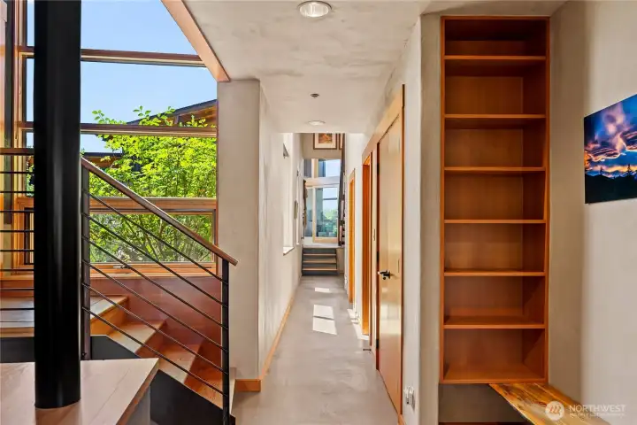 Looking back down light-filled the hallway toward the screened porch. Stairs down to the three car garage are just to the left, with a convenient bench and built in shelves to catch you and your things when you arrive home. Up the stairs to the left is a flexible-space studio or 1 bedroom apartment.