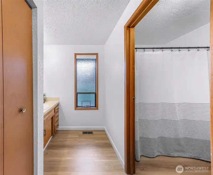 Shower and toilet are separated into their own portion of the bathroom.