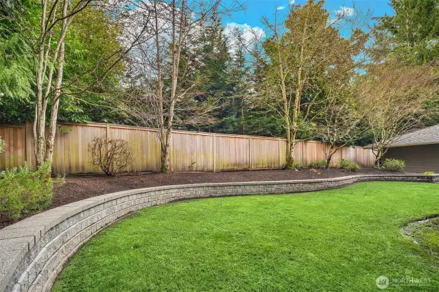 Level, grassy play lawn surrounded by a terraced planting bed.