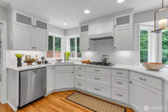 The kitchen boasts custom cabinetry, stunning quartz countertops, and stainless appliances, including a gas cooktop.