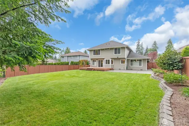 A spacious Trex deck and patio, surrounded by lush greenery on a green belt, provides privacy for relaxation and entertaining.