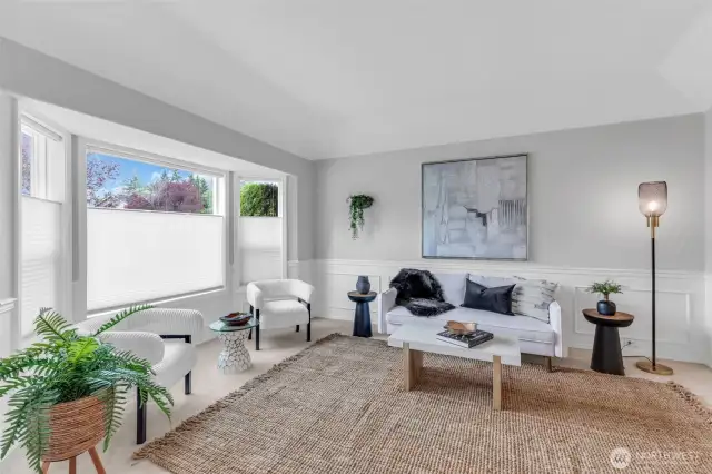 Living room features large windows that bring in natural light, creating an open atmosphere with high ceilings and comforable seating for relaxation and conversation.