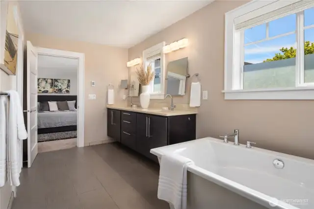 Looking across the bath back towards the bedroom the water closet is off to the left and there is also a second hookup for a washer and dryer. The spacious private bath boasts great counter space on floating wood cabinets with undermount sinks and a free standing tub plus a huge walk-in tiled shower (out of sight)