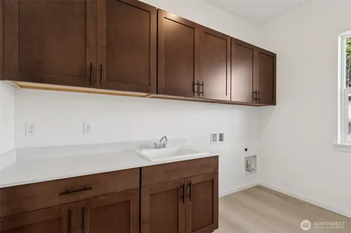 ***Actual Home *** Laundry with lots of cabinets, window for light and deep sink.
