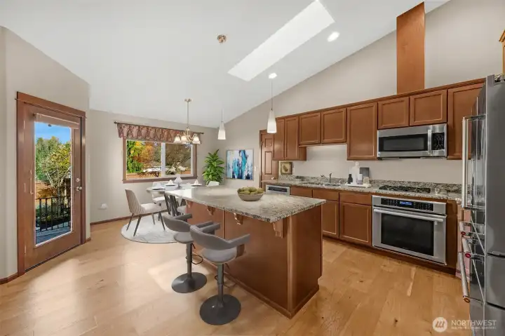 A bright kitchen with a skylight, a cozy dining room, and a counter designed for bar stools.
