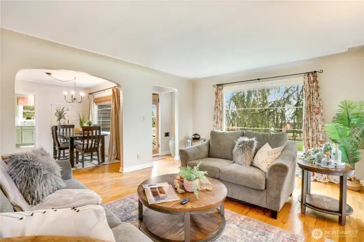 Bright and airy with timeless coved ceilings and rich hardwoods, the living room flows seamlessly through an arched opening into the dining space.