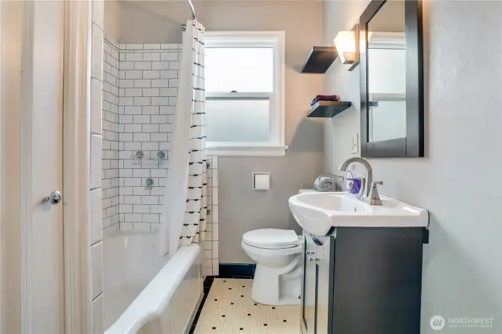 A blend of vintage charm and modern updates, featuring original tile flooring, refreshed surround tile, updated fixtures, and a refinished tub (all in 2022), along with excellent storage.