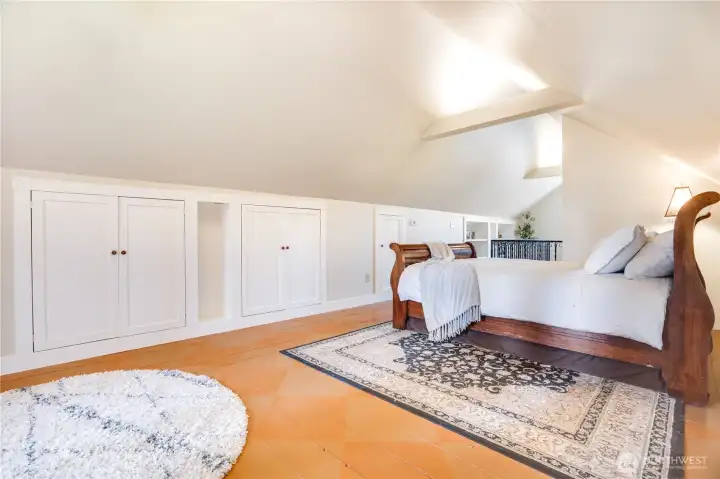 Eaves storage is thoughtfully integrated behind paneled doors along the walls, complemented by subtle wall niches that add both function and visual interest while keeping the space clean and uncluttered.