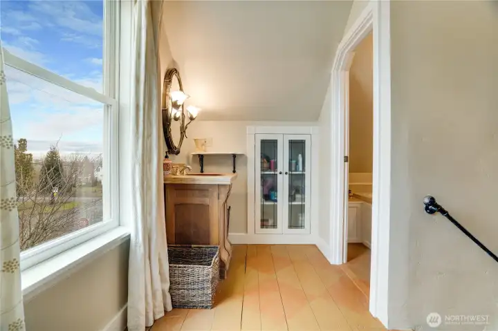 Charming details like a rustic vanity and built-in cabinetry with glass doors bring personality and warmth to the space.