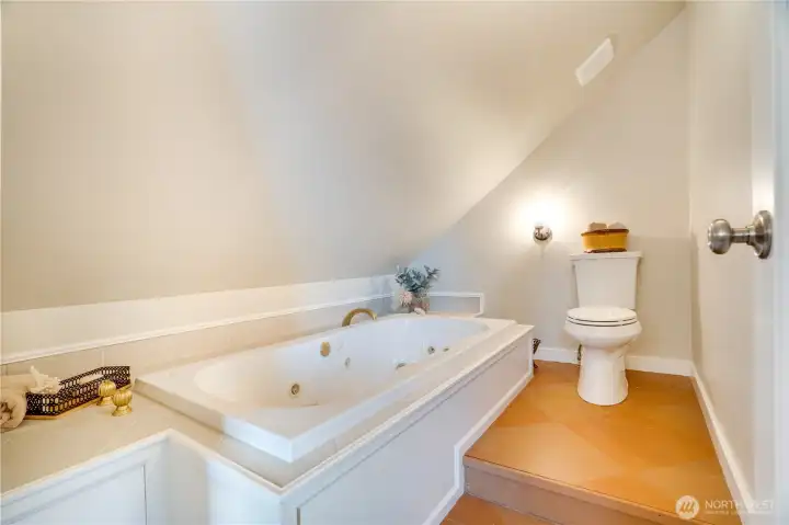 Unwind in the jetted spa tub beneath a surprisingly spacious ceiling—larger than it may appear in the photo—creating a comfortable and relaxing retreat.