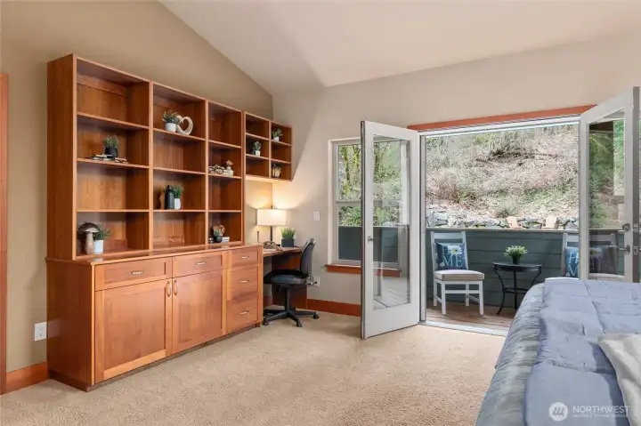 Primary suite features built-in cabinets and desk, French doors lead to private deck.