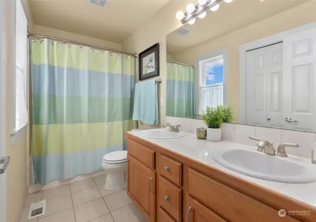 Discover a fully appointed guest bathroom, featuring a skylight that floods the space with natural light, double sinks for added convenience, an extra-long vanity offering ample storage and a linen closet to keep essentials neatly organized.