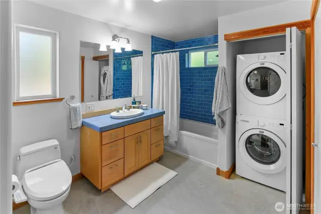 Main level Full bathroom with stacked washer dryer and storage area